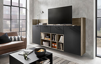 Modernes Wohnzimmer mit einer eleganten schwarzen Unterhaltungseinheit mit einem montierten Fernseher, ergänzt durch ein bequemes braunes Sofa und stilvolle Betonwände.
