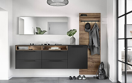 Moderno interno del bagno con elegante mobiletto in carbone, accenti in legno e decorazioni minimaliste, che creano uno spazio abitativo elegante e contemporaneo.