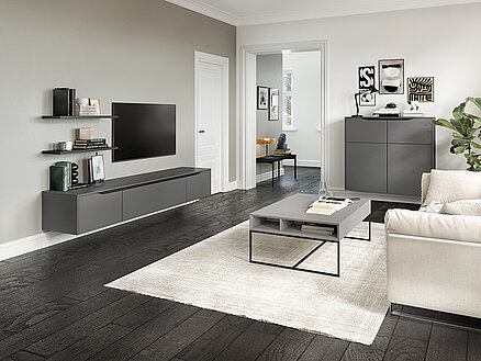 Moderne woonkamer met een minimalistisch ontwerp, met strak meubilair, neutrale kleuren en een goed georganiseerde entertainmentunit tegen een grijze muur.