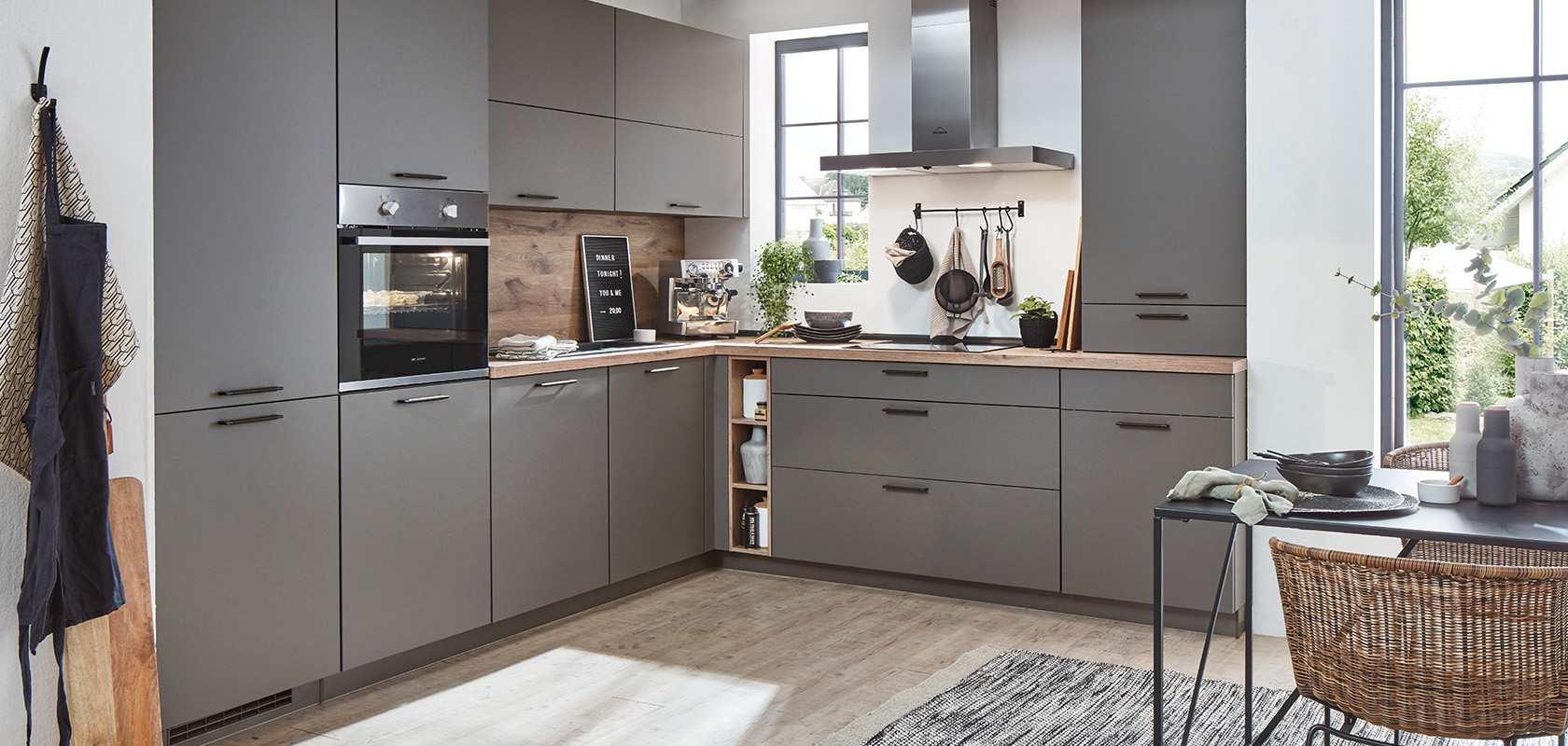 Moderne keuken met grijze kasten, houten werkbladen en roestvrijstalen apparaten, met een minimalistisch ontwerp en praktische elegantie.