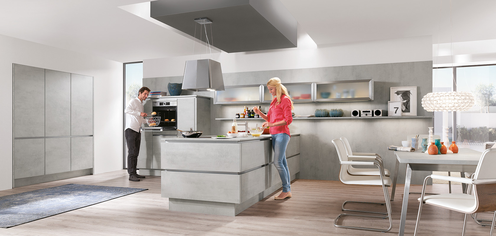 Un diseño de cocina moderna con dos personas cocinando, que cuenta con gabinetes elegantes, electrodomésticos de acero inoxidable y un diseño luminoso y espacioso.