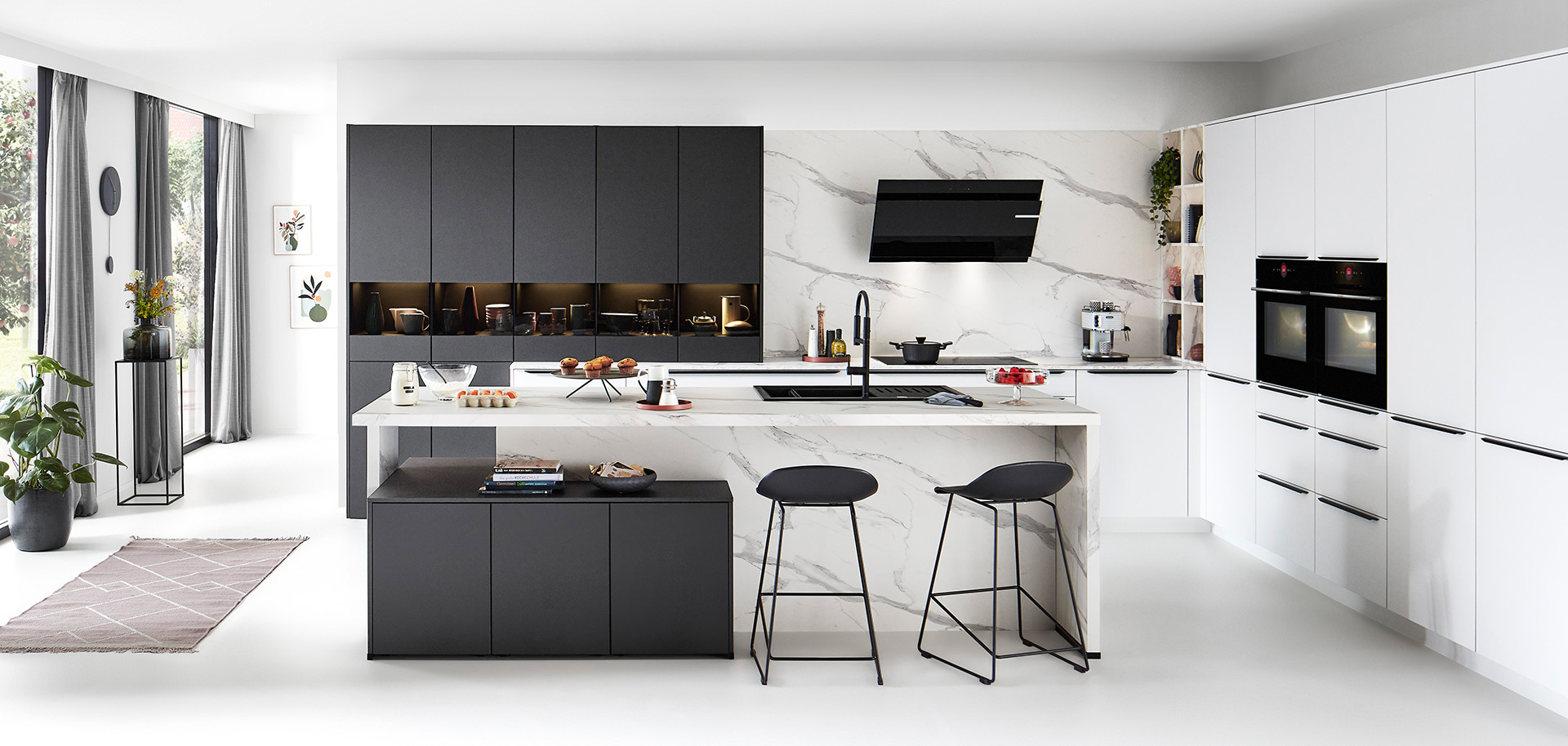 Moderne keuken met strakke lijnen, witte kasten, zwarte accenten, marmeren achterwand, geïntegreerde apparaten en een centraal eiland met barkrukken.