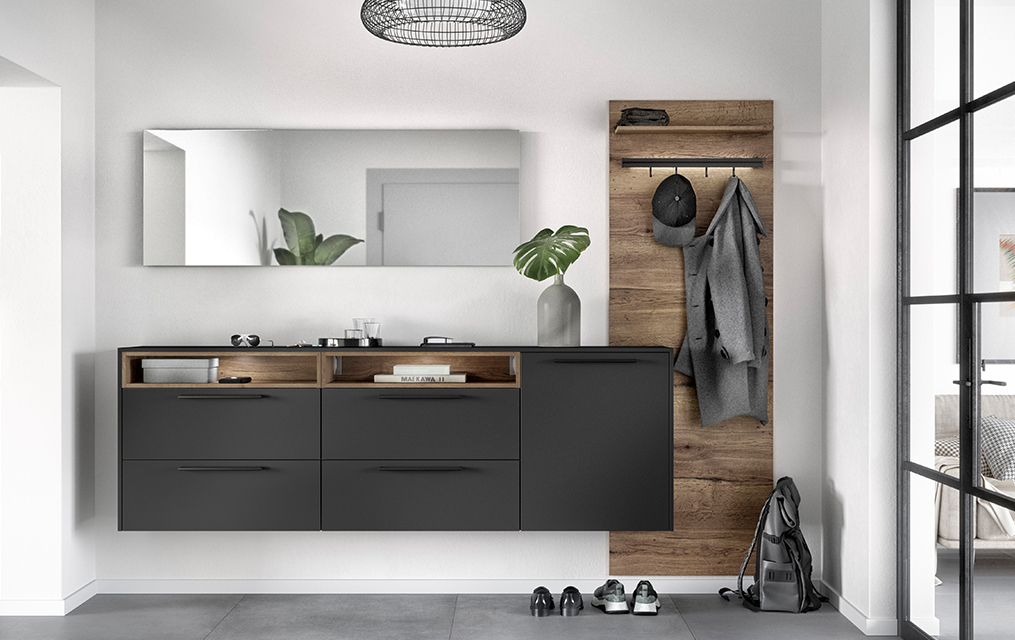 Modernes Badezimmerinterieur mit schlankem anthrazitfarbenem Waschtisch, Holzakzenten und minimalistischer Dekoration, das einen eleganten und zeitgenössischen Wohnraum vermittelt.