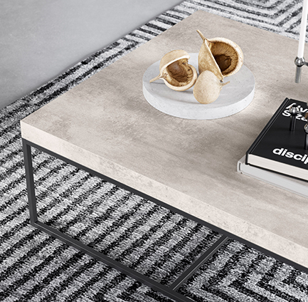 Table basse contemporaine dans un salon minimaliste, avec un dessus en béton lisse, un cadre métallique géométrique et une décoration artistique sur un tapis à motifs.