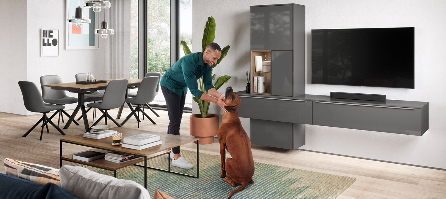 Een man interacteert met een hond in een stijlvolle, moderne woonkamer, met elegante meubels en een strak, eigentijds design esthetiek.
