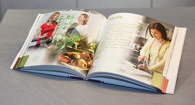 Ouvrez le livre de cuisine sur un plan de travail de cuisine avec des photographies colorées de nourriture et une personne en train de cuisiner, illustrant des instructions de recette claires et attrayantes.
