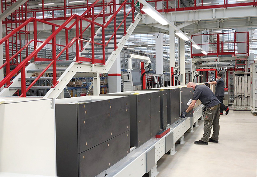 Un technicien inspecte des machines dans une installation industrielle moderne avec une disposition propre et organisée, mettant en valeur la précision et l'efficacité dans la fabrication.