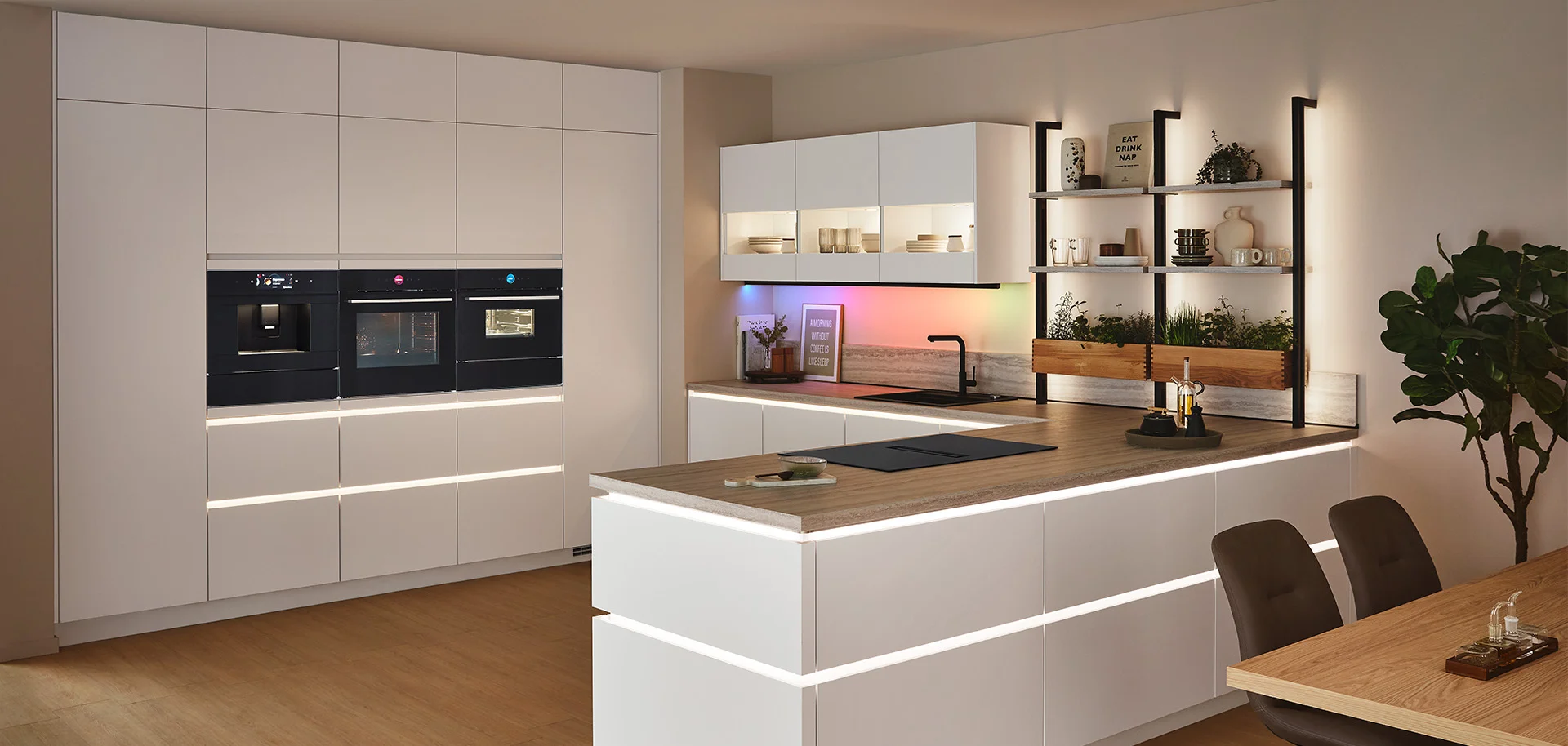 [Translate to it:] Moderne nobilia Küche mit Elektrogeräten, Front SENSO 490 in Alpinweiß Premium matt, grifflos mit LED-Lichtleisten und großzügiger Kochinsel für stilvolles Kochen und Wohnen.
