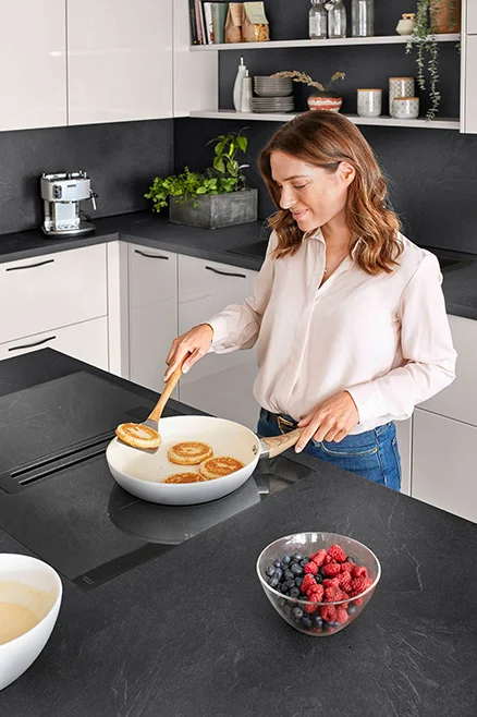 Vaření u varné desky s integrovaným odsavačem par - ergonomické řešení pro větší prostor nad hlavou.