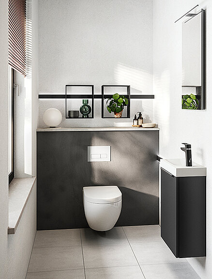 Elegantní moderní koupelna s vestavěným záchodem, matnými černými skříňkami s bílým pultem a minimalistickým dekorem s zelenými rostlinami.