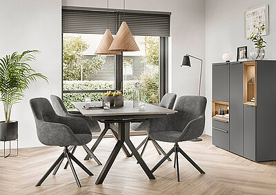 Moderní jídelna s minimalistickým designem, která má stylový tmavý dřevěný stůl, šedě čalouněné židle, visuté lampy a elegantní komodu.