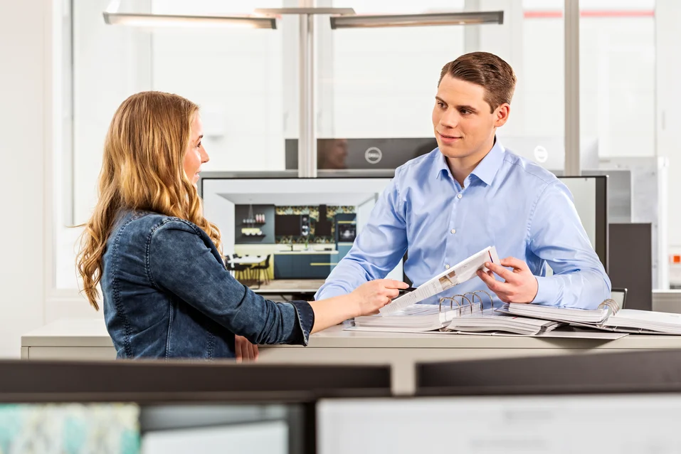 Zwei Personen arbeiten an einem Schreibtisch bei nobilia.