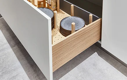 [Translate to nl:] Holzstäbe sichern Teller in SENSO 488 Alpinweiß. Stilvolle Kombination aus Holz und Front für Ordnung und Schutz im Alltag.