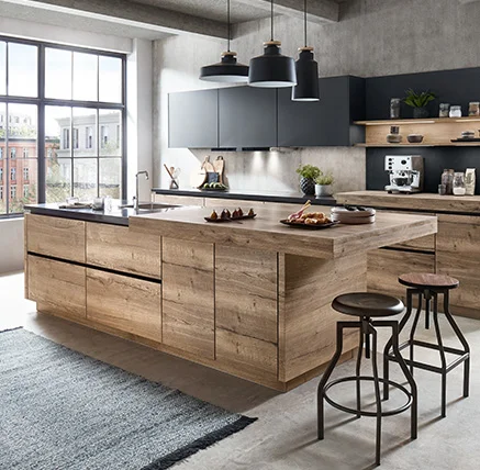 Cucina moderna con frontale STRUCTURA 402 in riproduzione rovere avana e piano di lavoro a sbalzo, aspetto rustico del legno abbinato a linee chiare e design nero delle pareti, la luce entra dalle ampie finestre.