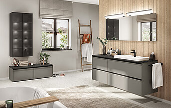 Moderne badkamer met een strakke wastafel met voldoende opbergruimte, grote spiegels en een rustgevend neutraal kleurenpalet, aangevuld met natuurlijke houtstructuren en groen.
