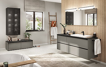 Modern bathroom featuring a sleek vanity with ample storage, large mirrors, and a calming neutral color palette, accented by natural wood textures and greenery.