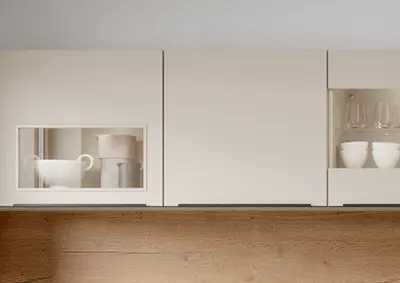 Wandschrank mit Glastür und Keramikgeschirr über einer hölzernen Küchenarbeitsplatte in heller Küche