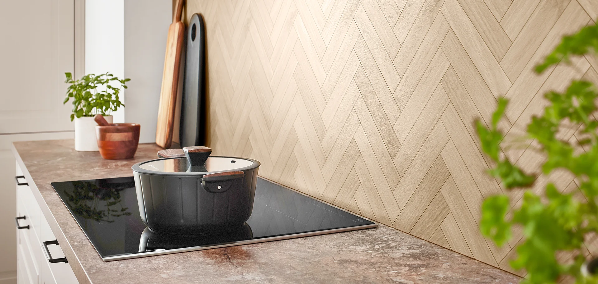 Moderne Küche mit eleganten schwarzen Marmor-Arbeitsplatten, goldenen Akzenten, Unterbaubeleuchtung und einem Topfpflanze, die einen Hauch von Grün verleiht.