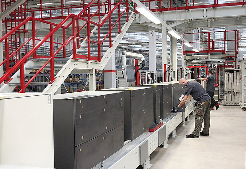 Technik kontroluje stroje v moderním průmyslovém zařízení s čistým a organizovaným uspořádáním, zdůrazňující přesnost a efektivitu ve výrobě.