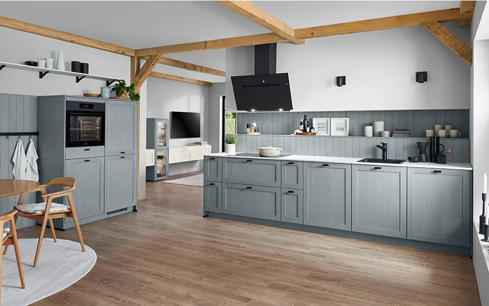Country-style kitchen in stone blue with FRAME 614 textured lacquered laminate front and continuous niche cladding in a matching color.