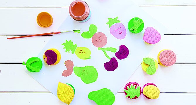 Bunte Schwamm-Malaktivität für Kinder auf einer weißen Oberfläche, mit Farbtöpfen und Pinseln, die Kreativität und Spaß mit Kunst fördert.