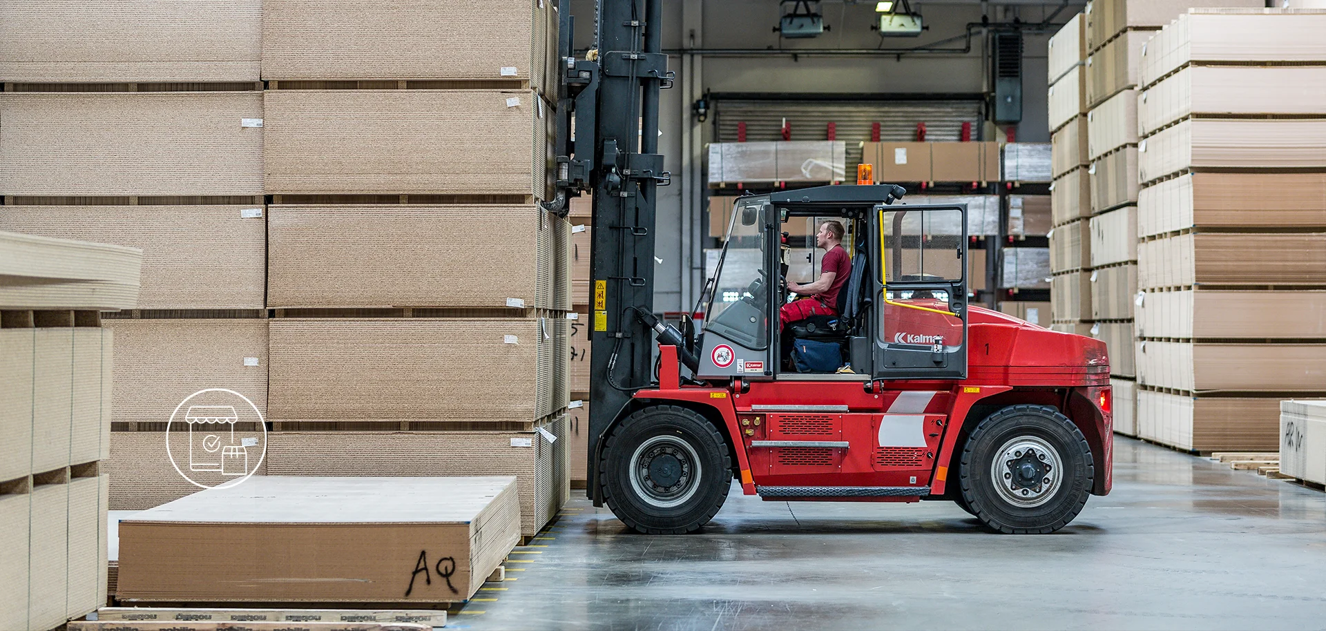 Roter Gabelstapler mit Fahrer zwischen hohen Stapeln von Holzplatten in einer Lagerhalle