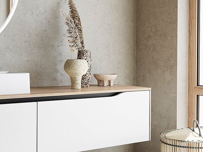 Elegante interno di casa con una console minimalista bianca con vasi decorativi e erba di pampas essiccata contro una parete grigia testurizzata, emanando un'estetica moderna.