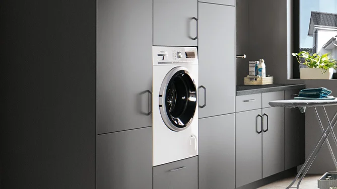 Lavatrice integrata nel ripostiglio nobilia con frontale TOUCH 334 in grigio pietra super opaco. Perfettamente integrata in un sistema di armadi funzionali per soluzioni domestiche moderne.