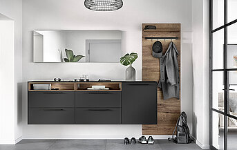 Moderní koupelnový interiér s elegantním uhlím šedým umyvadlovým stolem, dřevěnými doplňky a minimalistickým dekorem, vytvářející elegantní a současný obytný prostor.