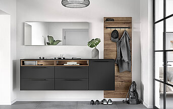 Moderne badkamerinterieur met strakke antraciet wastafel, houten accenten en minimalistische decoratie, wat resulteert in een elegante en eigentijdse leefruimte.