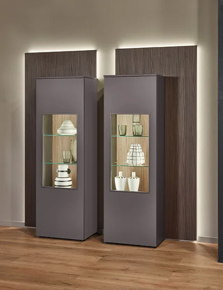 Beleuchtete Vitrine im Wohnzimmer mit Glaseinsatz, Holzrückwand und indirekter LED-Beleuchtung.