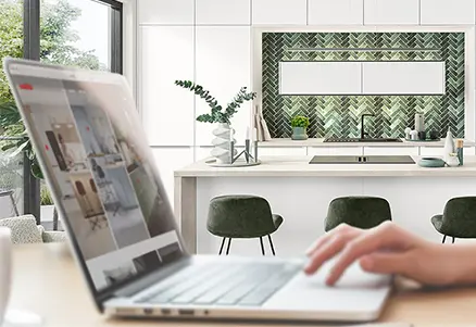 Weiße Küche mit grüner Nischenverkleidung im Hintergrund während Laptop mit nobilia Blog aufgerufen ist.