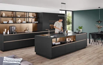 Cucina moderna con frontali in nero premium opaco della linea SENSO 496 e accenti dorati nella zona degli scaffali aperti.