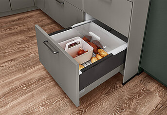 Cajón de cocina moderno parcialmente abierto revelando almacenamiento organizado con utensilios y alimentos, mostrando una utilización eficiente del espacio y un diseño contemporáneo.