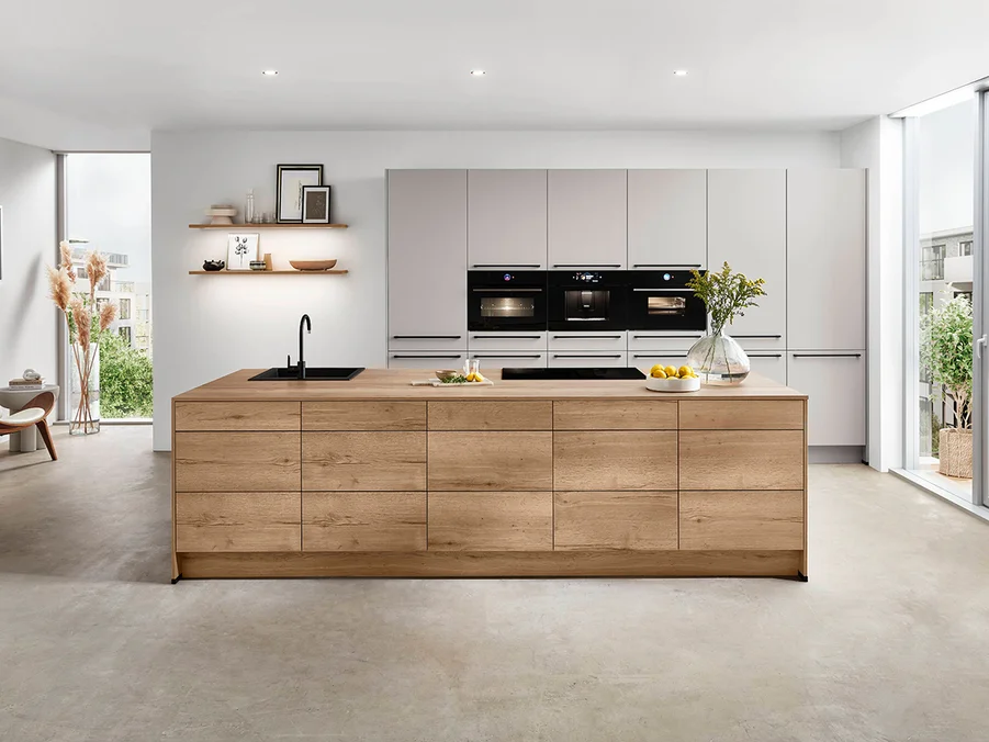 Moderne Kücheninsel aus Holz mit integriertem Kochfeld und Spüle, umgeben von eleganten Küchenschränken.