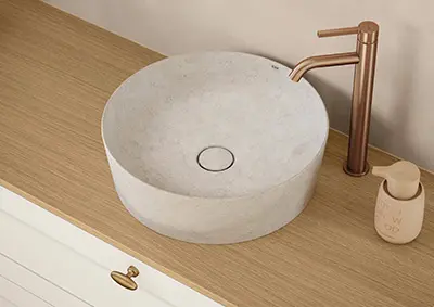Runder Aufbauwaschtisch SKIN in Natursteinoptik in Weiß auf Landhaus-Badmöbel mit Armatur in Bronze