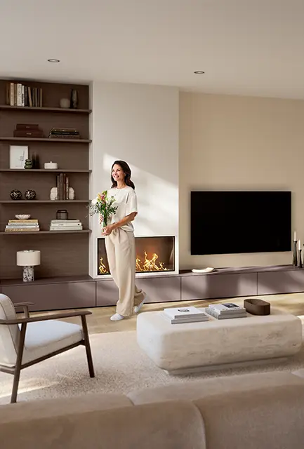 Wohnzimmer mit Frau, TV-Lowboard, Kamin und Regal in SENSO 498 Berry, mattem Lack mit Antifingerprint-Oberfläche