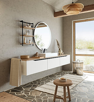 Minimalistyczne wnętrze łazienki z wiszącą toaletką, okrągłym lustrem, naturalnymi teksturami i spokojnym widokiem pustyni przez okno.