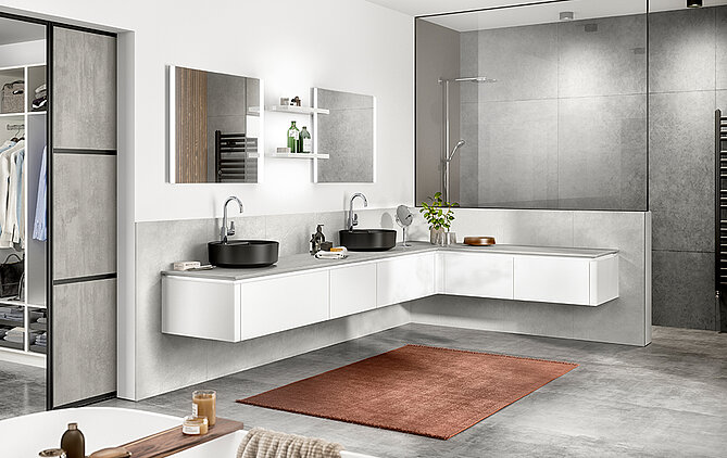 Baño moderno con un elegante tocador de doble lavabo, espejo grande, ducha a ras de suelo y acentos en tonos cálidos destacados en un diseño limpio y minimalista.