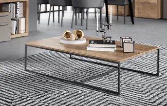 Sala de estar moderna que muestra una elegante mesa de centro de madera con patas de metal, colocada sobre una alfombra con patrón geométrico en un entorno interior contemporáneo.