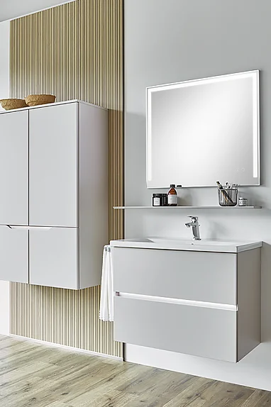 Bathroom furniture with central recessed grip and illuminated mirror for modern design and clear lines.
