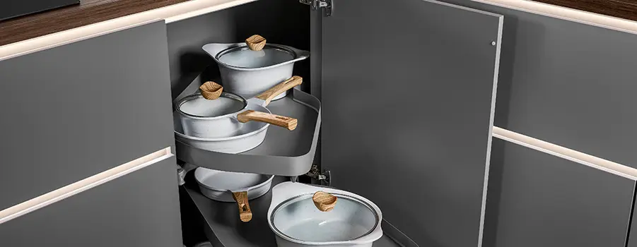 Kochgeschirr in einer Eckschranklösung unter der Küchenarbeitsplatte, organisiert und platzsparend angeordnet.