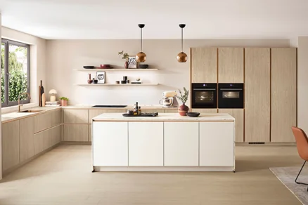 Gemütliche Küche mit weißer Kücheninsel, Softline Front in Weiß und Hochschränken in Eiche Como mit Bronze-Details