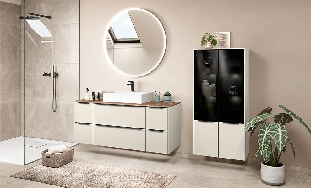 Stilvolle Badplanung mit warmweißen Magnolia-Fronten mit Anti-Fingerprintoberfläche, Waschtischplatte in Marmoroptik Venato Rosso, Aufsatzwaschtisch, Rundspiegel und Dusche