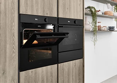 [Translate to pl:] nobilia Kompaktgeräte in schwarzem Design – moderne Einbaubacköfen in ergonomischer Höhe, platzsparend integriert in Holzoptik-Küchenfronten für stilvolle und funktionale Küchenlösungen.