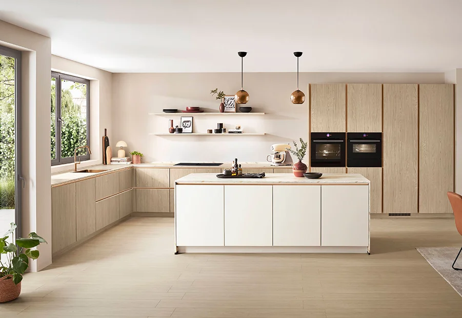 Moderne Küche mit hellen Holzfronten, eleganter Kochinsel und stilvollen Pendelleuchten in einem lichtdurchfluteten Raum.