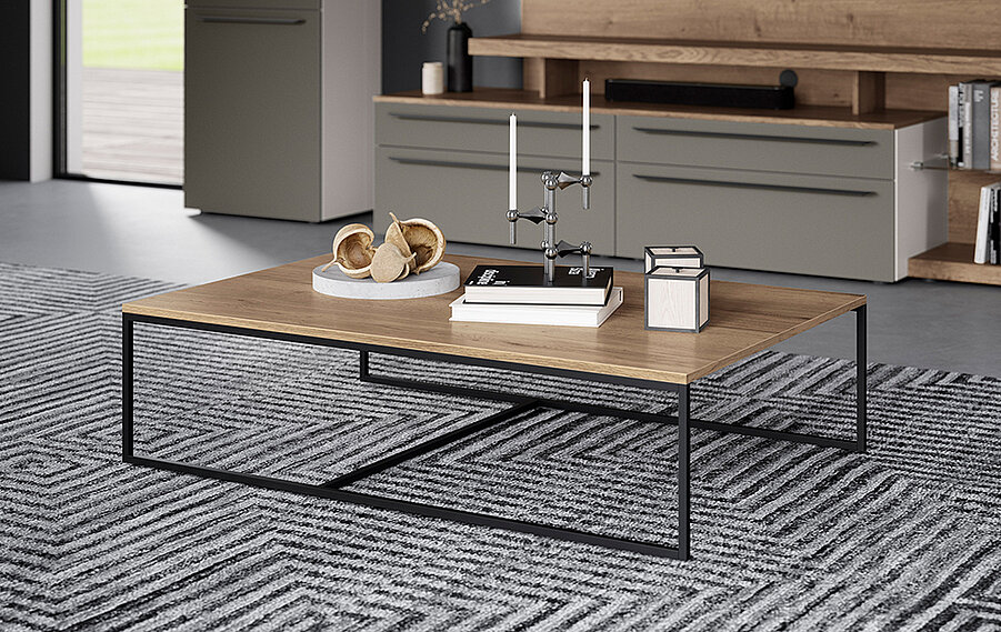 Ein modernes Wohnzimmer mit einem stilvollen Couchtisch mit Metallbeinen, dekorativen Objekten und einem strukturierten Teppich in einem schicken, minimalistischen Interieur.