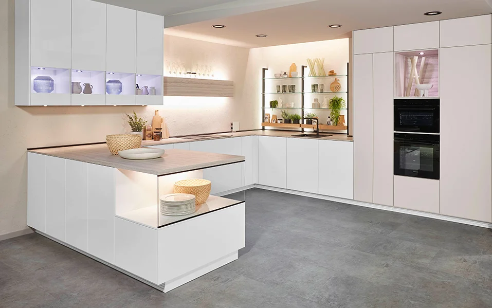 U-shaped kitchen with Novalux 516 front in high-gloss white, elegant integrated electrical appliances, modern room design with open shelf lighting and generous work surface.