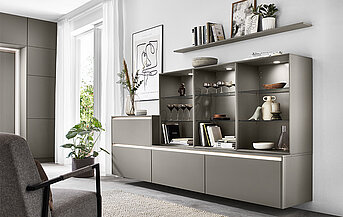 Interior moderno de una sala de estar con elegantes unidades de estanterías modulares, mostrando libros y decoración, complementado por muebles minimalistas y luz natural.