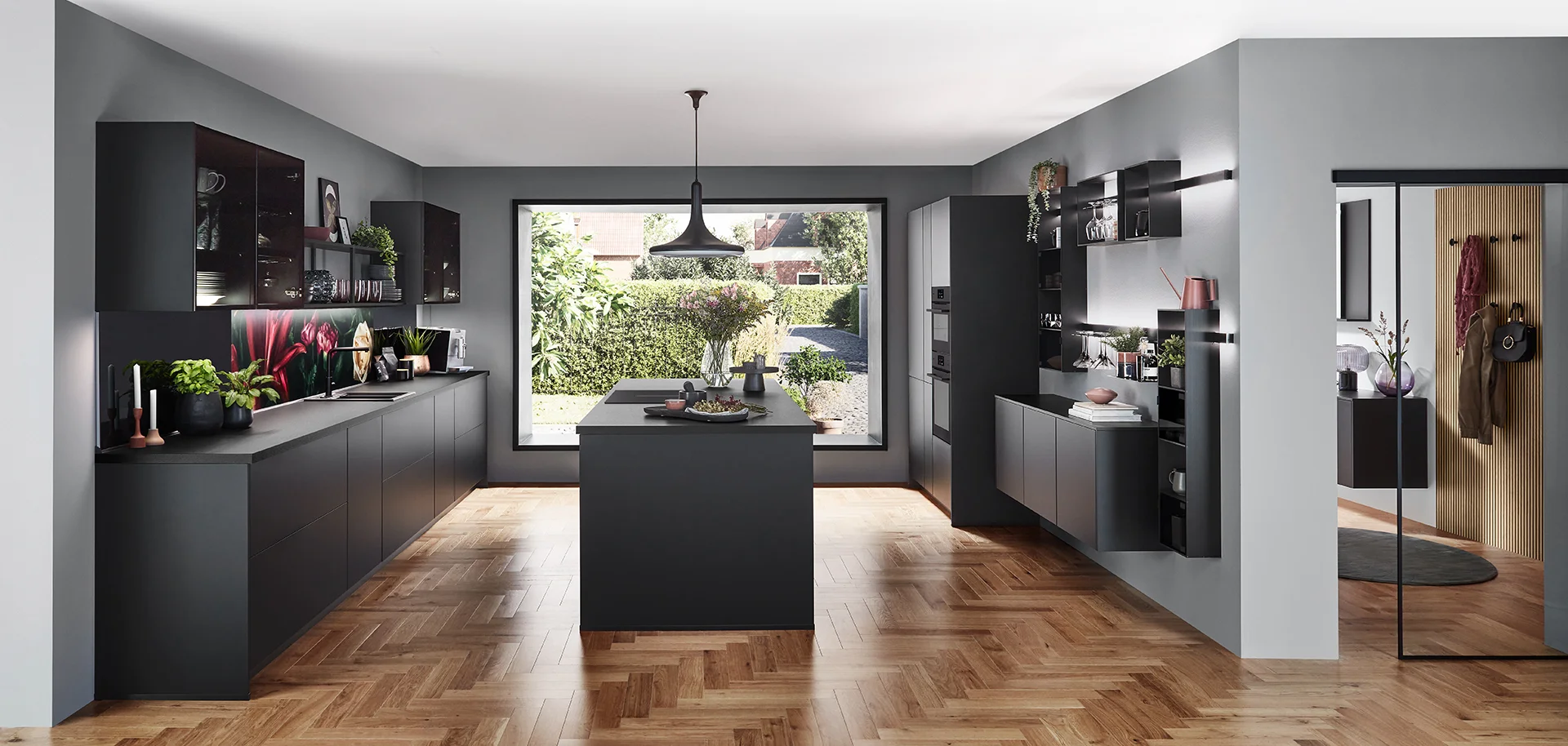 Zeitgemäße Küche mit schwarzen Arbeitsplatten, weißen Schränken, stilvollen Pendelleuchten und einem Fenster mit Blick auf grünes Laub.